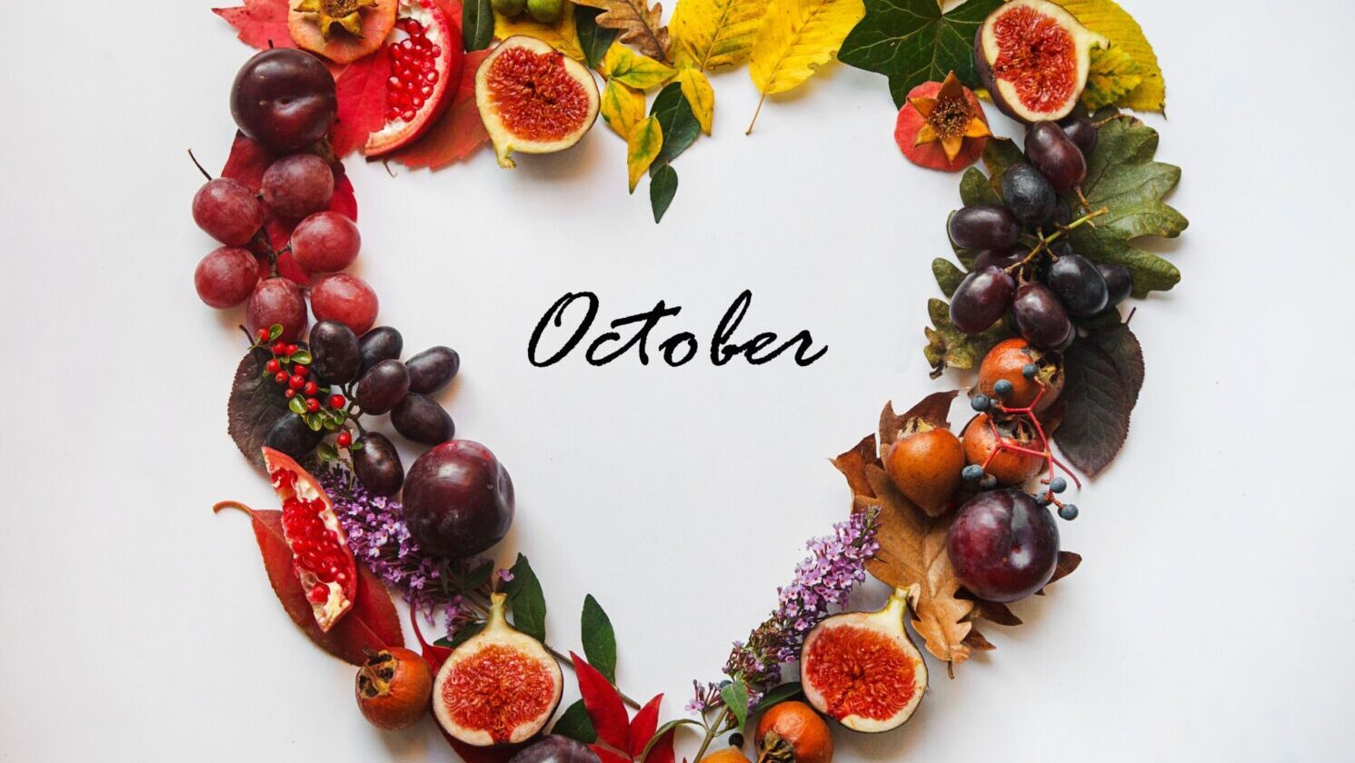 Autumnal heart-shaped wreath made of fruit and leaves, symbolizing October's beauty.